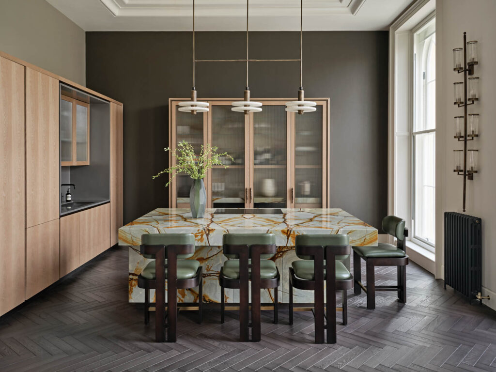 a moody kitchen with a pale green marble island bar in a London home