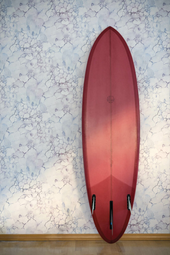 a pink surfboard against a wall covered in the Aquarelle wallpaper
