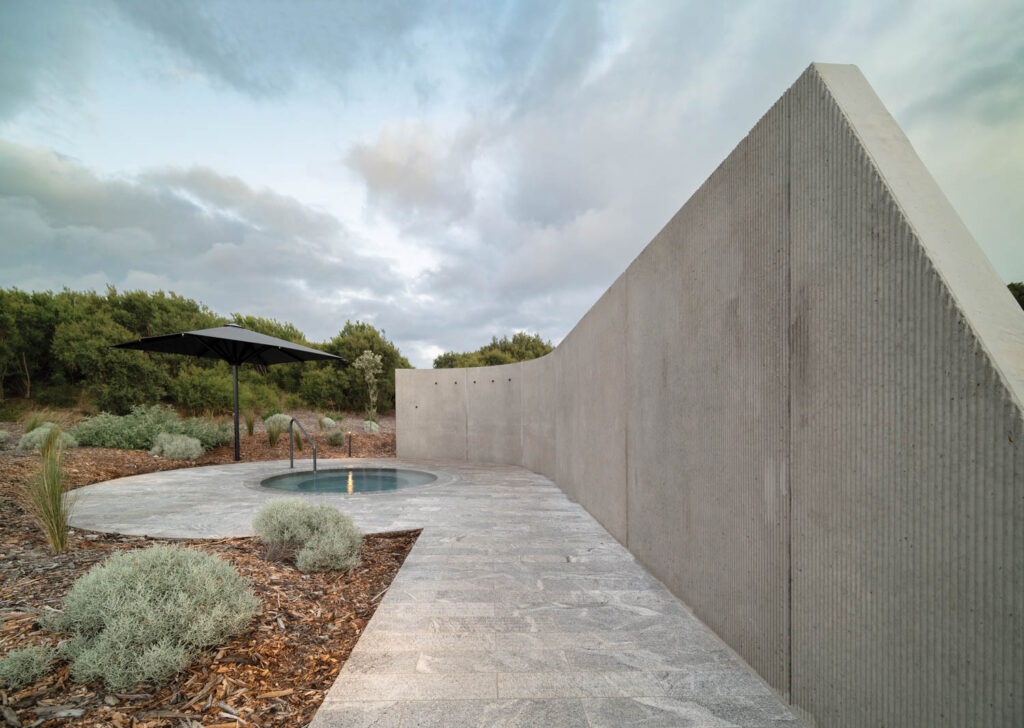 a thermal pool surrounded by a curving concrete wall with a ribbed surface