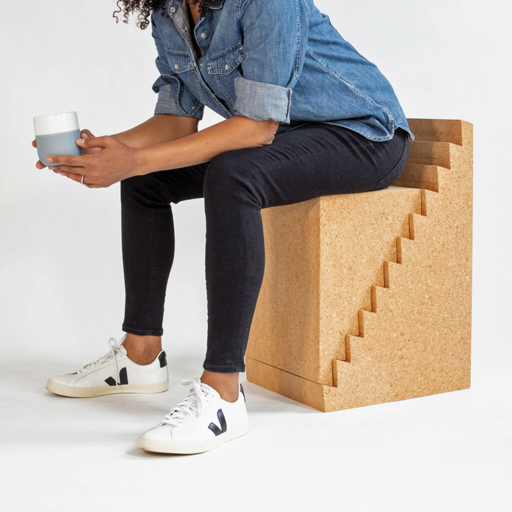 a woman sits on top of a cork furniture unit