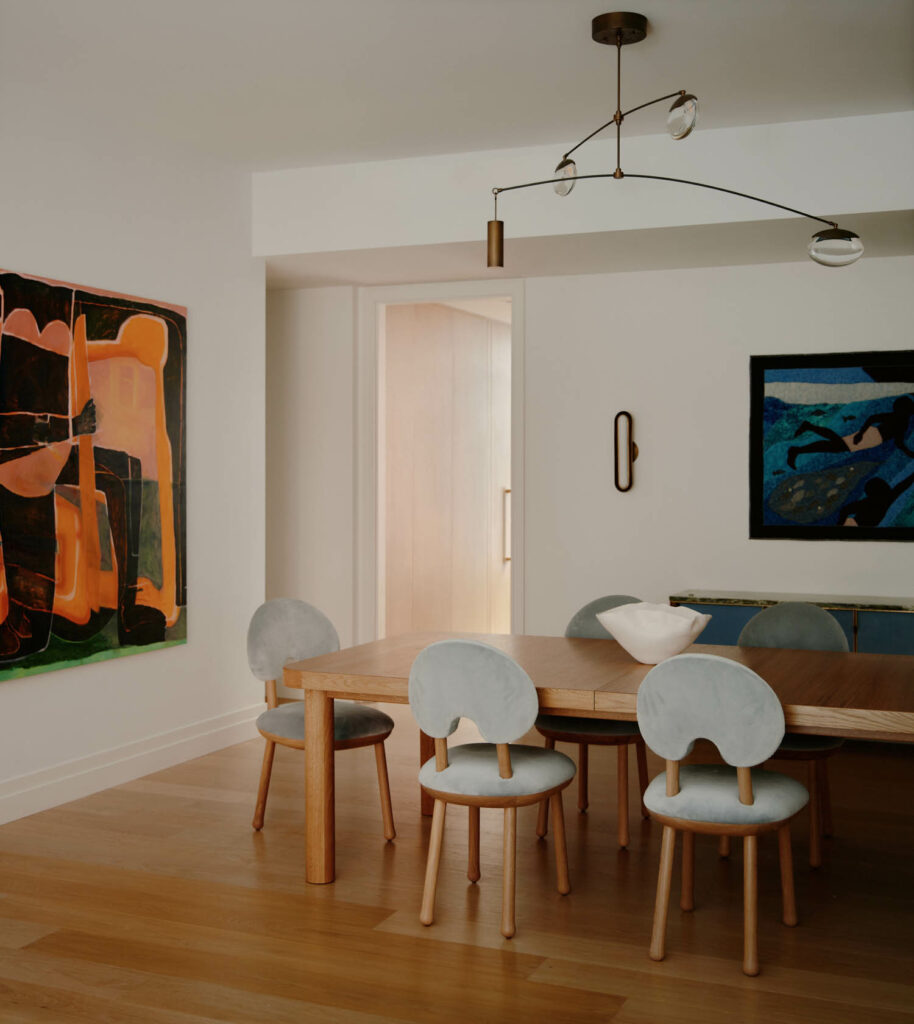 the dining area of a Tribeca home with an abstract, vibrant artwork on one wall