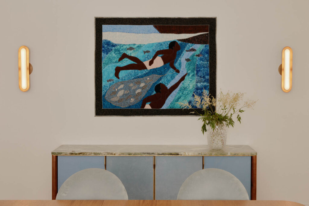 a blue credenza under a quilt artwork by Stephen Towns