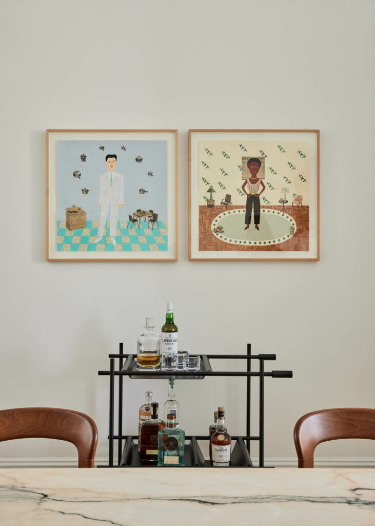 a bar cart sits below two artworks by Lucy Fradkin